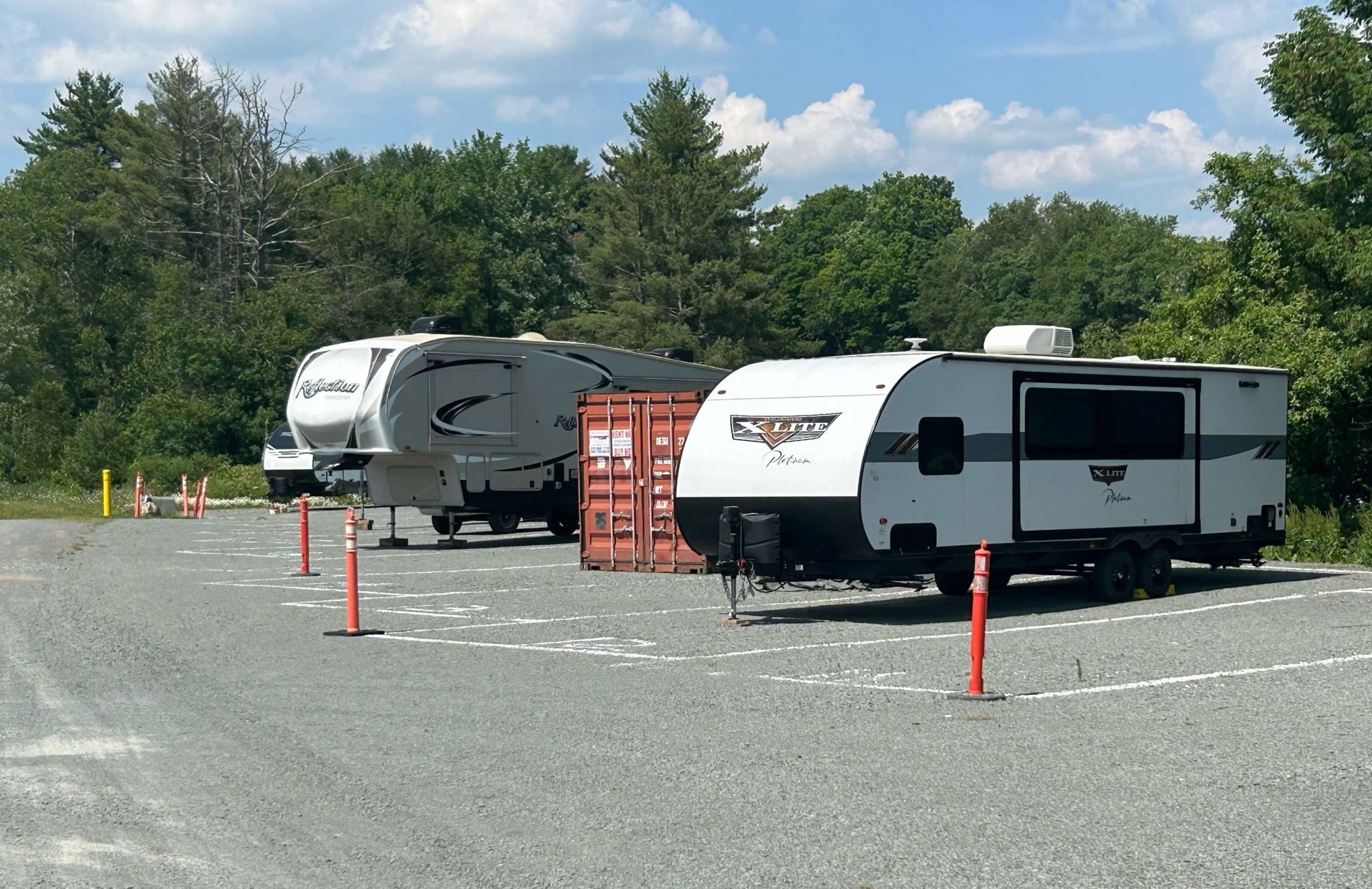 RVs and a shipping containing parked outdoors in their vehicle storage parking lot